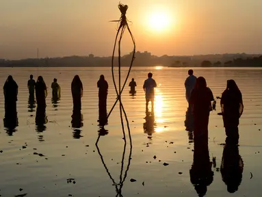 Umat Hindu India memanjatkan doa pada matahari pada festival Chhath di tepi Danau Hussain Sagar di Hyderabad, Selasa (17/11). Dalam festival tersebut, sejumlah umat Hindu berdoa saat matahari terbit dan tenggelam. (AFP PHOTO/NOAH Seelam)