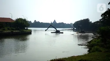 Petugas menggunakan alat berat untuk mengeruk lumpur di Setu Babakan, Jakarta, Selasa (30/6/2020). Pengerukan dilakukan guna mengembalikan kedalaman setu sehingga menambah daya tampungnya. (Liputan6.com/Immanuel Antonius)