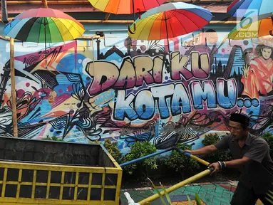 Warga melintasi gambar mural/grafiti di Kampung Bekelir, Jalan Perintis Kemerdekaan, Kota Tangerang, Banten, Selasa (17/4). Kampung Bekelir pada 10 tahun lalu merupakan kawasan yang kumuh. (Merdeka.com/Arie Basuki)
