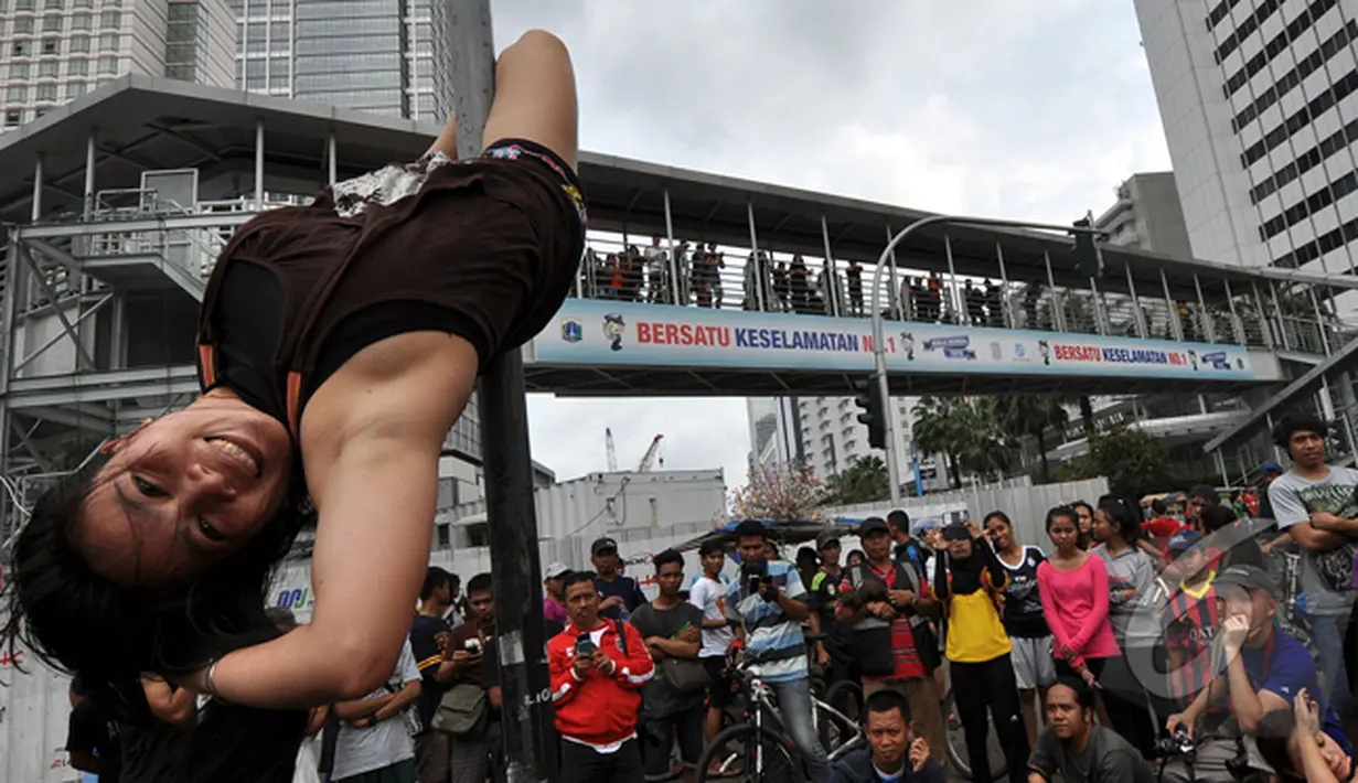 Tiang rambu lalu lintas menjadi arena aksi dari pegiat 'Pole Dance'  di Bundaran HI, Jakarta, Minggu (18/1/2015). (Liputan6.com/Miftahul Hayat)