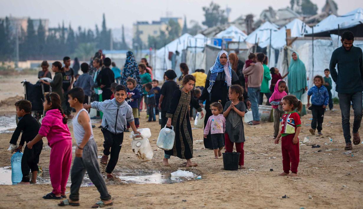 Pipa-pipa utama rusak parah, menyebabkan jaringan distribusi air lumpuh. Tampak dalam foto, orang-orang mengisi wadah air mereka di kamp Nuseirat untuk pengungsi Palestina di Jalur Gaza tengah pada Kamis 4 Desember 2025. (Eyad Baba/AFP)