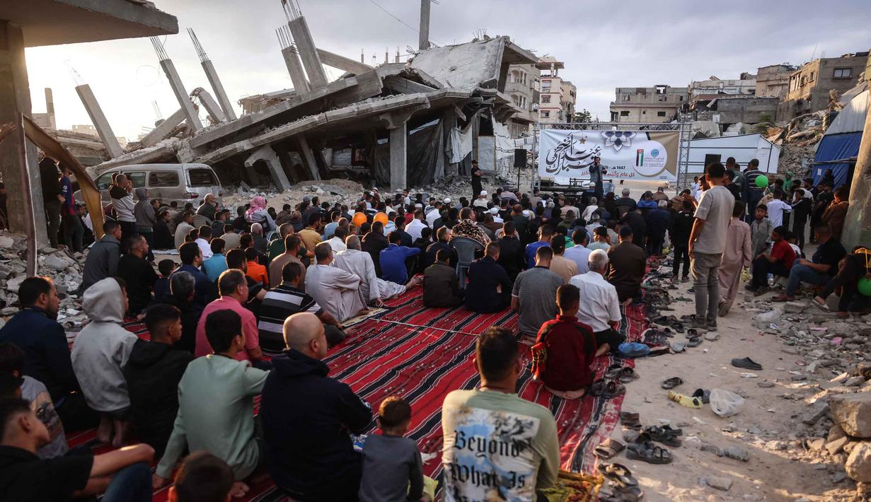 Warga Palestina berkumpul di jalan yang rusak parah untuk melaksanakan salat menandai dimulainya Idul Adha, Hari Raya Kurban, di Khan Yunis, Jalur Gaza Selatan, pada Rabu 27 Mei 2026. (BASHAR TALEB/AFP)