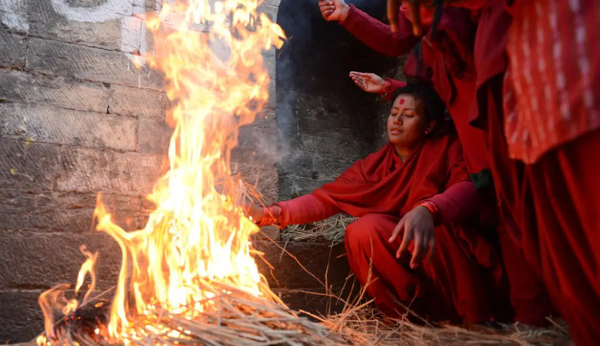 Para wanita hindu Nepal menghangatkan badan usai mandi di Sungai Bagmati saat Festival Swasthani, Kathmandu, Selasa (20/1/2015). (AFP Photo/Prakash Mathema)