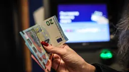 Penerapan euro akan dilakukan secara bertahap. Sepanjang Januari 2026, masyarakat Bulgaria masih diperbolehkan menggunakan dua mata uang secara bersamaan, Lev Bulgaria tetap berlaku berdampingan dengan euro selama masa transisi tersebut. Tampak dalam foto, seseorang menunjukkan uang kertas euro yang ditarik dari ATM di Sofia, Bulgaria, Kamis 1 Januari 2026, saat negara tersebut bergabung dengan serikat mata uang euro. (AP Photo/Valentina Petrova)