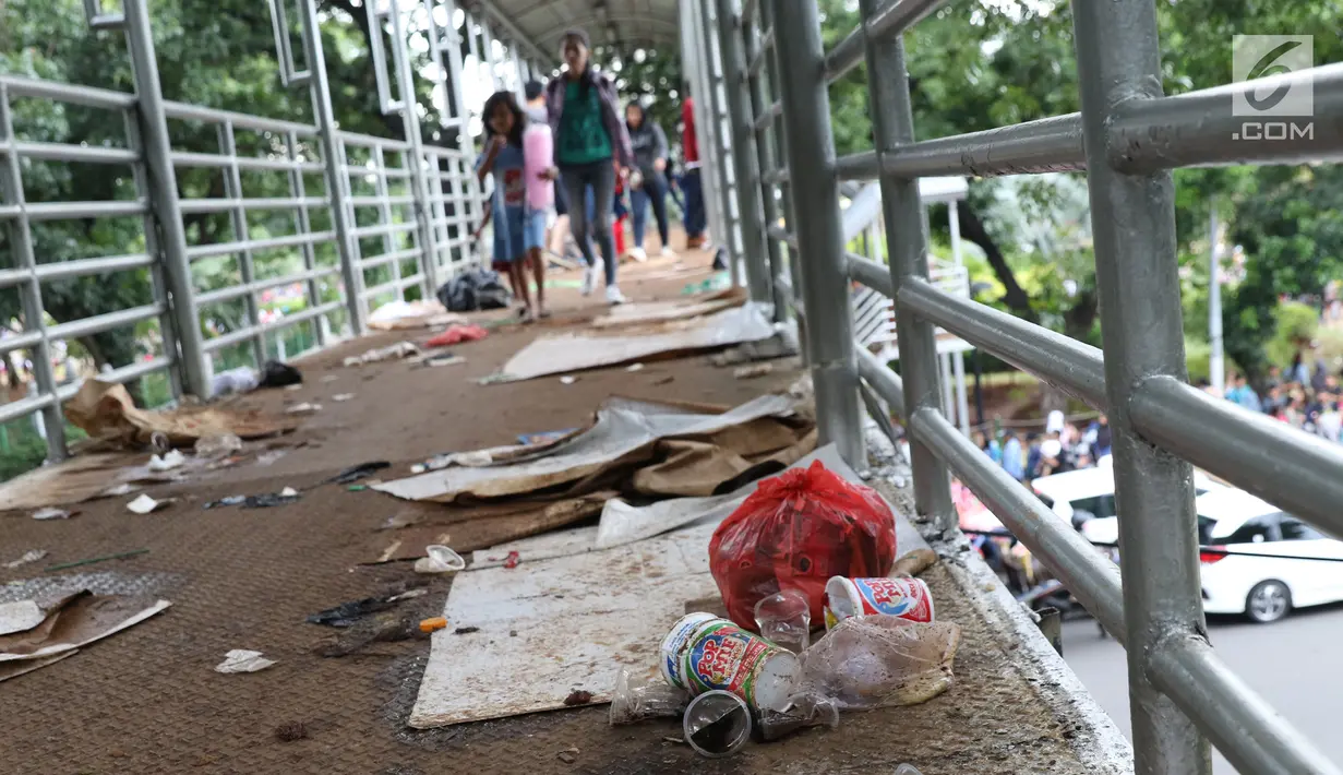 Sampah berserakan di koridor Jembatan Penyebrangan Orang (JPO) Jalan Medan Merdeka Barat, Jakarta, Selasa (1/1). Pasca malam perayaan pergantian tahun JPO Medan Merdeka Barat masih tampak kotor. (Liputan6.com/Helmi Fithriansyah)