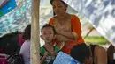 Seorang ibu dan anaknya berteduh di sebuah taman setelah gempa dan tsunami melanda Palu di Sulawesi Tengah, Selasa (2/10). Data terbaru BNPB menunjukkan, korban tewas akibat tsunami dan gempa di Sulawesi Tengah sudah mencapai 1.347 orang. (AFP/BAY ISMOYO)