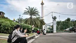 Warga menikmati sore hari di depan gerbang masuk Monumen Nasional (Monas), Jakarta, Minggu (15/11/2020). Meski masih ditutup untuk umum sejak awal pandemi Covid-19, kawasan Monas tetap ramai dikunjungi warga untuk sekadar mengisi akhir pekan. (merdeka.com/Iqbal S Nugroho)