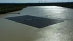 Pemandangan dari udara menunjukkan panel surya dengan turbin angin di kejauhan di pabrik fotovoltaik terapung di danau Silbersee di Haltern, Jerman barat (22/4/2022). Taman surya terapung terbesar di Jerman saat ini sedang dibangun. (AFP/Ina Fassbender)