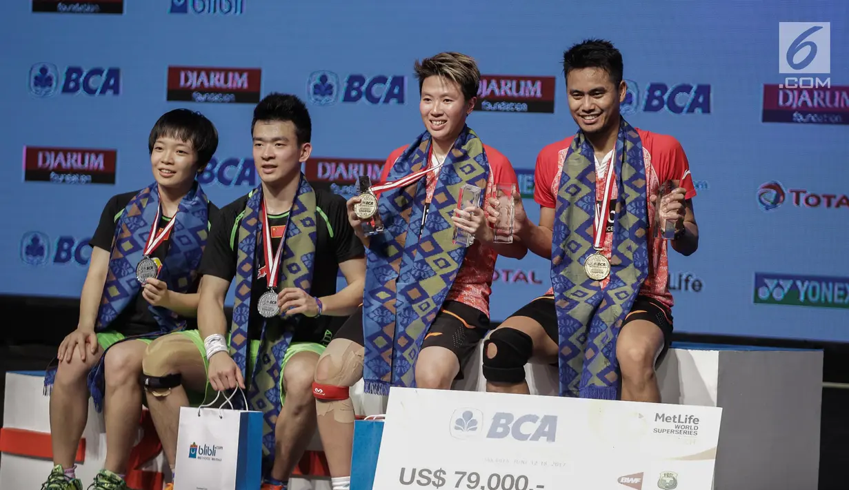 Ganda Campuran Indonesia, Tontowi Ahmad/Liliyana Natsir menunjukan medali dan giant cheque US$79 ribu usai mengalahkan Ganda Campuran Zheng Siwei/Chen Qingchen dalam final BCA Indonesia Open 2017 di Jakarta, Minggu (18/6). (Liputan6.com/Faizal Fanani)