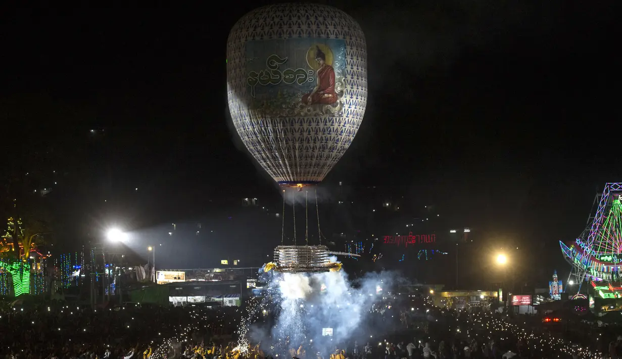 Peserta melepaskan balon udara yang membawa lentera kecil selama Festival Tazaungdaing di Taunggyi, Myanmar pada 14 November 2018. Perayaan festival ini digelar saat bulan purnama bersinar di langit malam Myanmar. (Ye Aung THU / AFP)