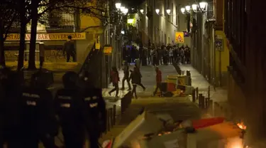 Petugas polisi saat terlibat bentrok dengan imigran di Madrid, Spanyol, Kamis (15/3). Bentrokan berawal dari aksi protes imigran atas meninggalnya seorang pedagang jalanan asal Senegal. (AFP Photo/Olmo Calvo)