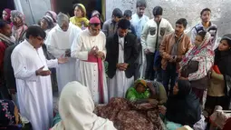 Pemuka agama berdoa di dekat jenazah korban minuman keras oploson di Toba Tek Singh, sekitar 338 km dari Islamabad, Selasa (27/12). Selain memakan korban jiwa, minuman oplosan rumahan itu juga membuat puluhan orang dilarikan ke rumah sakit. (STR/AFP)