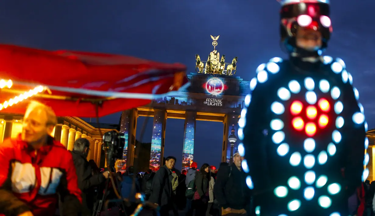 Wisatawan mengamati Gerbang Brandenburg yang dihiasi cahaya saat pembukaan Festival cahaya, Jerman, Sabtu (10/10/2015). Festival ini merupakan event tahunan yang diadakan setiap bulan Oktober selama dua belas hari.(REUTERS/Hannibal Hanschke)