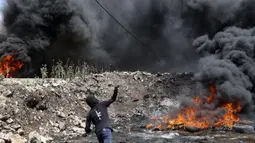 Seorang pengunjuk rasa Palestina melemparkan batu ke pasukan keamanan Israel di tengah bentrokan menyusul demonstrasi menentang perampasan tanah Israel di Desa Kfar Qaddum dekat pemukiman Yahudi Kedumim, Tepi Barat, 6 Mei 2022. (JAAFAR ASHTIYEH/AFP)