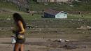 Seorang wanita berjalan di dekat rumah perahu yang terkena dampak kekeringan dekat Sungai Solimões, Tefe, Amazonas, Brasil, Rabu (19/10/2022). Kapal-kapal besar yang mengangkut bahan kebutuhan harus mencari rute alternatif. (AP Photo/Edmar Barros)
