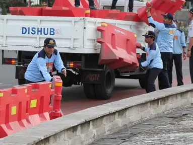 Petugas Dinas Perhubungan menata pembatas jalan untuk menutup sejumlah titik di kawasan Bundaran HI, Jakarta, (31/12). Gubernur DKI Jakarta Basuki Tjahaja Purnama mengatakan perayaan tahun baru akan dibagi dibeberapa wilayah. (Liputan6.com/Angga Yuniar)