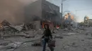 Seorang wanita berjalan di samping bangunan-bangunan yang rusak parah akibat serangan Rusia di Kyiv pada Minggu 24 Mei 2026, di tengah invasi Rusia ke Ukraina. (Roman PILIPEY/AFP)