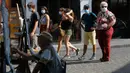 Pelukis terlihat saat turis berjalan-jalan di distrik Montmartre, Paris pada Senin (10/8/2020). Penggunaan masker mulai hari Senin (10/8) diwajibkan di area luar ruangan yang ramai di ibu kota Prancis itu untuk mengendalikan peningkatan tingkat infeksi virus corona. (AP Photo/Michel Euler)