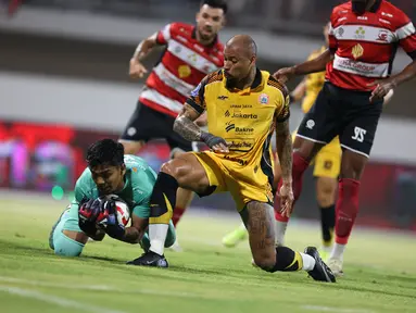 Pemain Persija Jakarta, Gustavo Almeida (kanan) berduel dengan kiper Madura United pada lanjutan BRI Super League 2025/2026 di Stadion Gelora Ratu Pamelingan, Jumat (24/10/2025) malam WIB. (Bola.com/Abdul Aziz).