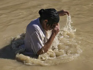 Seorang peziarah Kristen Ortodoks membenamkan dirinya ke Sungai Yordan saat upacara pembaptisan pada perayaan Epiphany di Qasr el Yahud, dekat kota Yerikho, Tepi Barat, 18 Januari 2022. Sungai Yordan dipercaya menjadi tempat di mana Yesus dibaptis. (AP Photo/Mahmoud Illean)