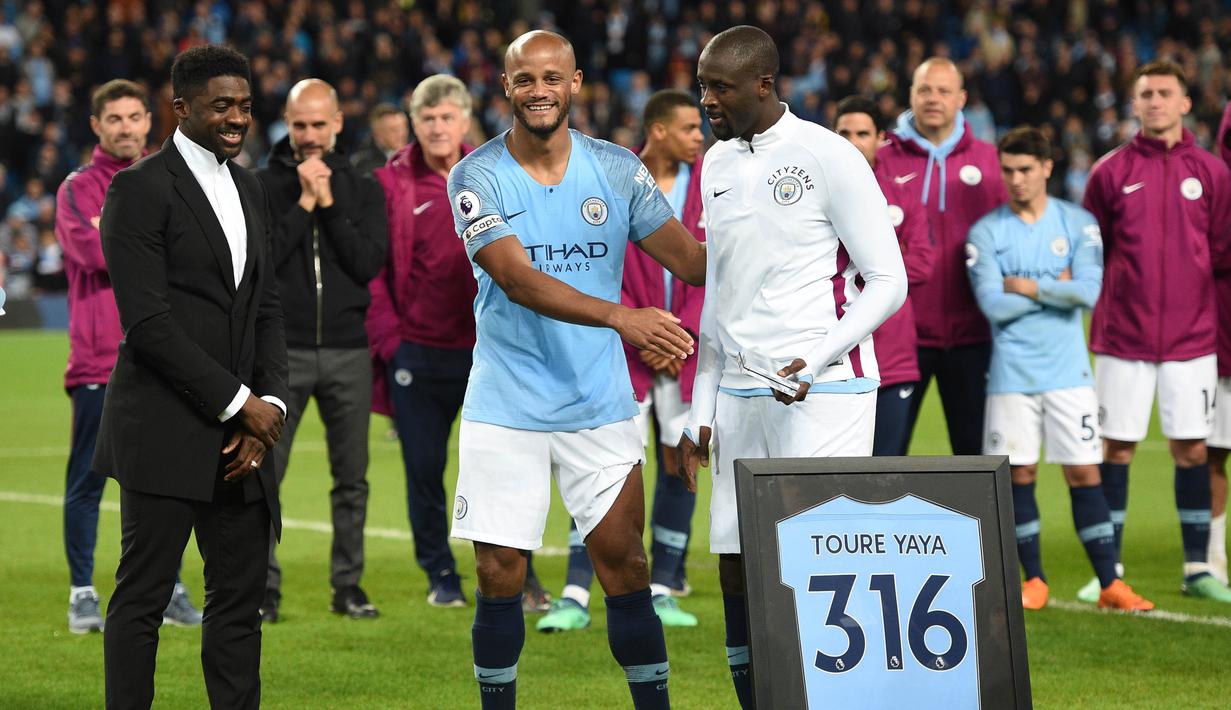 Kapten Manchester City, Vincent Kompany, mendampingi Yaya Toure saat perpisahan di Stadion Etihad, Rabu (9/5/2018). Laga tersebut menjadi ajang perpisahan sang pemain bersama The Citizens. (AFP/Oli Scarff)