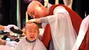 Seorang anak dicukur saat upacara berjudul 'Anak-anak Menjadi Buddha Monks', di kuil Jogye, Seoul, Rabu (19/4). Setelah upacara anak-anak akan tinggal di kuil selama dua minggu untuk mengikuti perayaan ulang tahun Buddha. (AFP PHOTO / JUNG Yeon-Je)