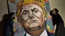 Seniman Ukraina Daria Marchenko dan Seniman Inggris Daniel Green menunjukkan lukisan Presiden AS Donald Trump yang terbuat dari rangkaian koin di Akademi St George di New York (30/1). (AFP Photo/Don Emmert)