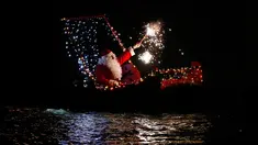 Seorang pria mengenakan kostum Santa Claus bermain kembang api di atas kapal selama perayaan malam Natal di Imperia, Italia (24/12). (AP Photo/Antonio Calanni)