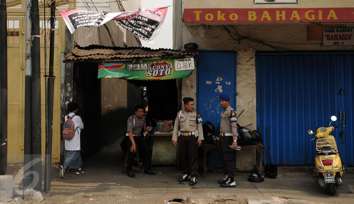 Beberapa petugas kepolisian berjaga di salah satu gang masuk menuju kawasan Kampung Pulo Jakarta, Jumat (21/8/2015). Ribuan aparat gabungan terus berjaga mengawal proses penggusuran warga Kampung Pulo Jakarta Timur. (Liputan6.com/Helmi Fithriansyah)