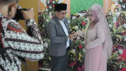 Suasana prosesi pernikahan sepasang pengantin di KUA Pamulang, Tangerang Selatan, Selasa (22/2/2022). Sebanyak 10 pasangan menjalankan akad nikah di KUA Pamulang pada hari ini yang dianggap memiliki tanggal cantik. (merdeka.com/Arie Basuki)