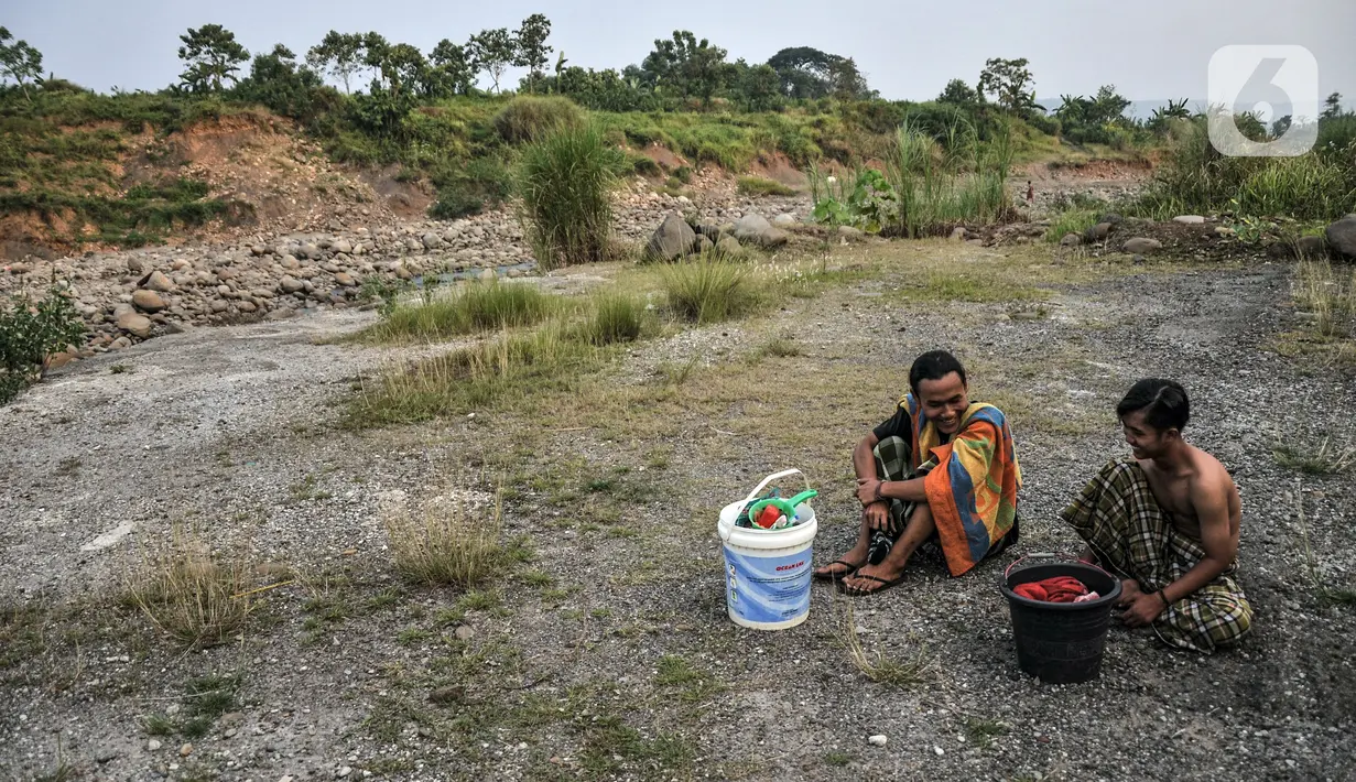 Dua warga menunggu giliran untuk mandi di Sungai Cipamingkis, Desa Jagaita, Jonggol, Kabupaten Bogor, Jawa Barat, Kamis (29/7/2021). Warga mandi dan mencuci pakaian di aliran Sungai Cipamingkis lantaran sumur di rumah mereka mengalami kekeringan sejak satu bulan lalu. (merdeka.com/Iqbal S. Nugroho)