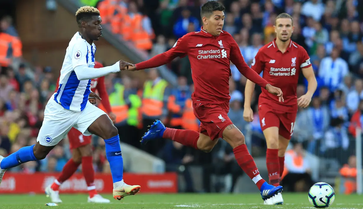 Penyerang Liverpool, Roberto Firmino berusaha menendang bola dari kawalan pemain Brighton and Hove Albion, Yves Bissouma saat bertanding pada lanjutan Liga Inggris di Anfield Stadium (25/8). Liverpool menang atas Brighton 1-0. (AFP Photo/Lindsey Parnaby)