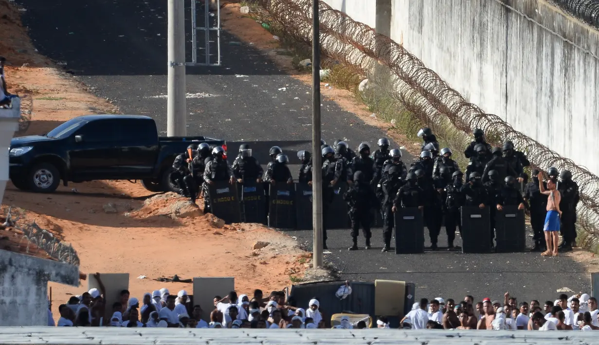 Seorang tahanan berbicara dengan polisi setelah bentrokan di penjara Alcacuz, Natal, Rio Grande do Norte, Brasil, (16/1). Polisi harus menggunakan peluru karet untuk membubarkan bentrokan antar geng tersebut. (AFP Photo/Andressa Anholette)