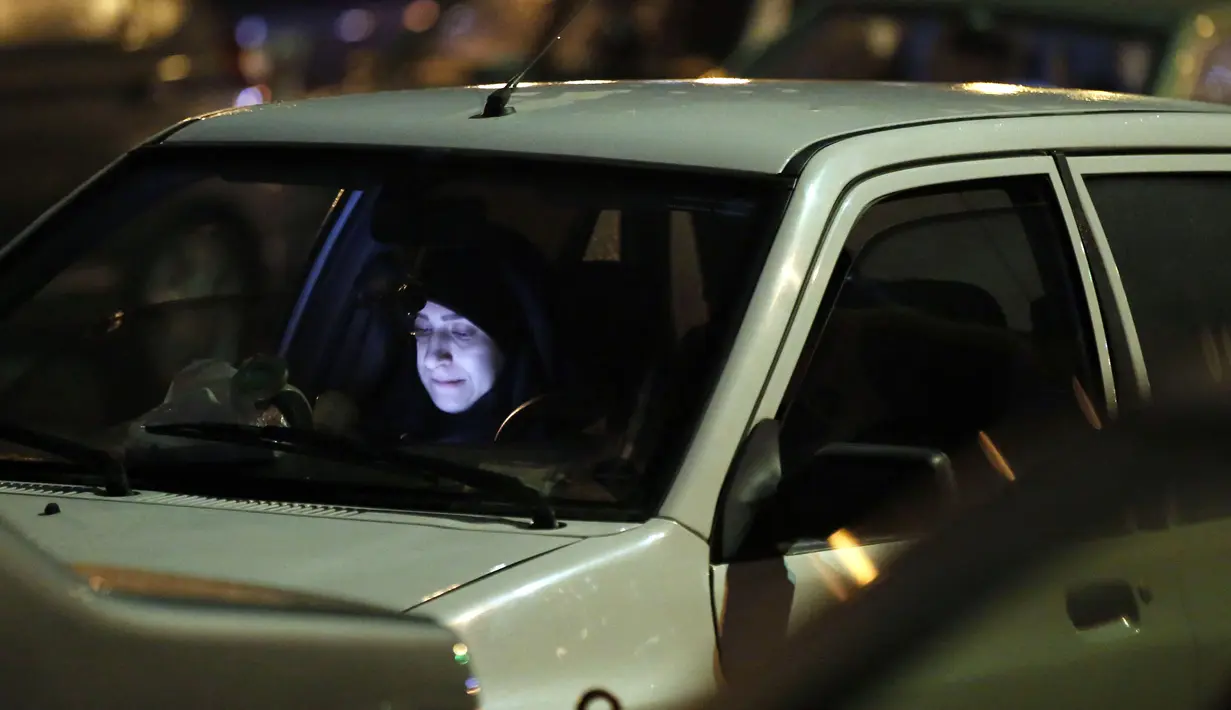 Wanita membaca Al-Quran dalam mobil saat upacara keagamaan pada bulan suci Ramadan di tengah pandemi COVID-19, Teheran, Iran, Kamis (30/4/2020). Keluarga-keluarga di Iran menghadiri upacara keagamaan drive-in karena tidak memiliki kesempatan untuk salat di masjid setelah berbuka puasa. (STR/AFP)