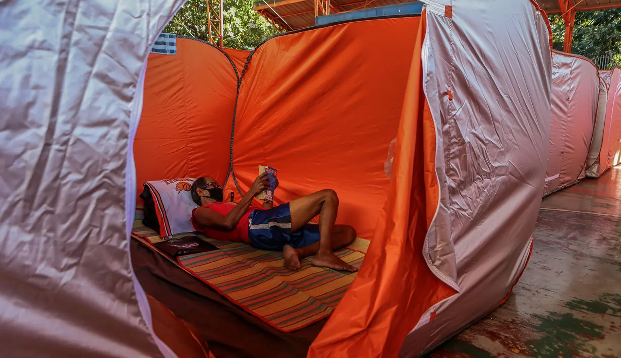 Warga membaca buku di sebuah tenda modular bagi kaum tunawisma guna menghentikan penyebaran COVID-19 di sebuah lapangan basket beratap di Manila, 23 Maret 2020. Jumlah kasus infeksi virus corona meningkat menjadi 501, menurut Otoritas kesehatan Filipina, pada Selasa (24/3). (Xinhua/Rouelle Umali)