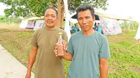 Warga Kampung Segeram, Kabupaten Natuna, Awang (kiri) dan Syahrul Nizam (kanan) memegang sebotol calok, kuliner khas kampung mereka. (Liputan6.com/Asnida Riani)