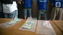 Barang bukti kasus pemalsuan surat hasil rapid test COVID-19 diperlihatkan dalam rilis di Mapolres Jakarta Pusat, Minggu (20/12/2020). Polisi menangkap tiga tersangka beserta bukti uang hasil transaksi pemalsuan surat hasil rapid test COVID-19. (Liputan6.com/Faizal Fanani)