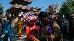 Anggota komunitas Newar mengenakan kostum dan masker saat berpartisipasi dalam prosesi 'Gai Jatra', atau festival sapi, di Kathmandu, Nepal, Selasa (4/8/2020). Festival ini untuk meminta keselamatan dan kedamaian bagi orang yang mereka cintai yang telah meninggal. (AP Photo/Niranjan Shrestha)