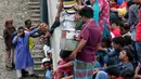 Seorang wanita berusaha naik ke atap kereta api saat akan pulang kampung di stasiun kereta api di Dhaka, Bangladesh, (22/6). Ribuan yang bekerja di Dhaka pulang ke kampung halamannya untuk merayakan lebaran bersama keluarganya. (AP Photo/A.M.Ahad)