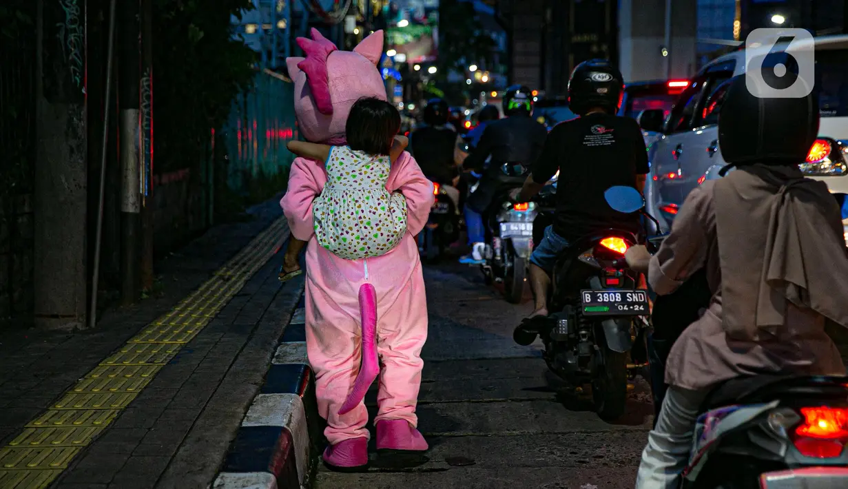 Warkuatno (41) bersama anak sulungnya, Bunga (9) berjalan kaki di pinggir Jalan Raya Fatmawati, Cilandak, Jakarta, Rabu (6/1/2021). Warkuatno harus memutar otak demi bisa bertahan hidup usai kehilangan pekerjaannya. (Liputan6.com/Faizal Fanani)