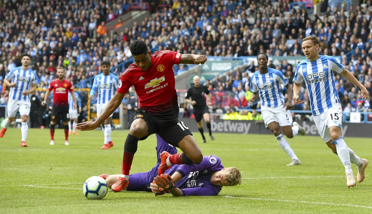 Penyerang Manchester United, Marcus Rashford, berusaha melewati kiper Huddersfield Town, Jonas Lossl, pada laga Premier League di Stadion John Smith, Minggu (5/5). Kedua tim bermain imbang 1-1. (AP/Anthony Devlin)