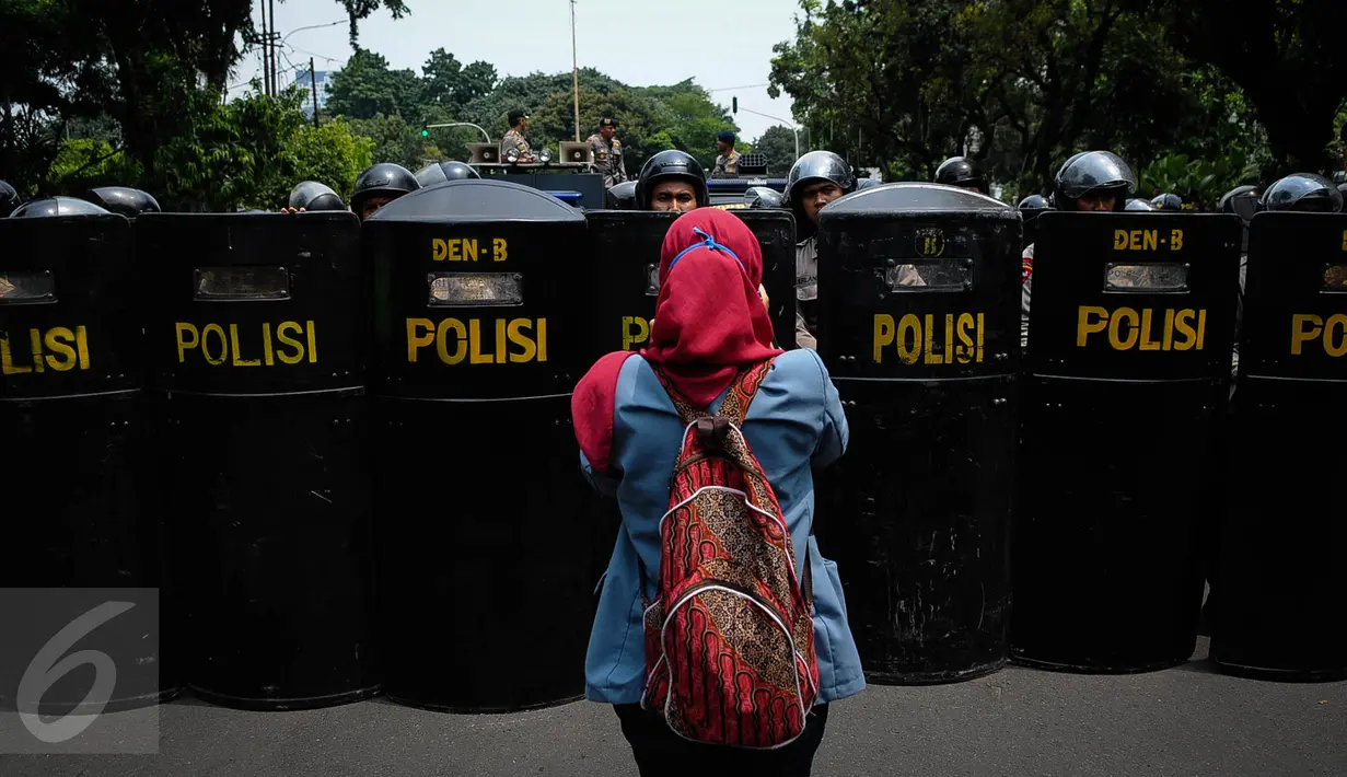 Seorang mahasiswa mengabadikan penjagaan kepolisian saat aksi demonstrasi di Istana Negara, Jakarta, Kamis (20/10). Aksi yang dilakukan mahasiswa merupakan peringatan tepat dua tahun pemerintahan Joko Widodo-Jusuf Kalla. (Liputan6.com/Faizal Fanani)