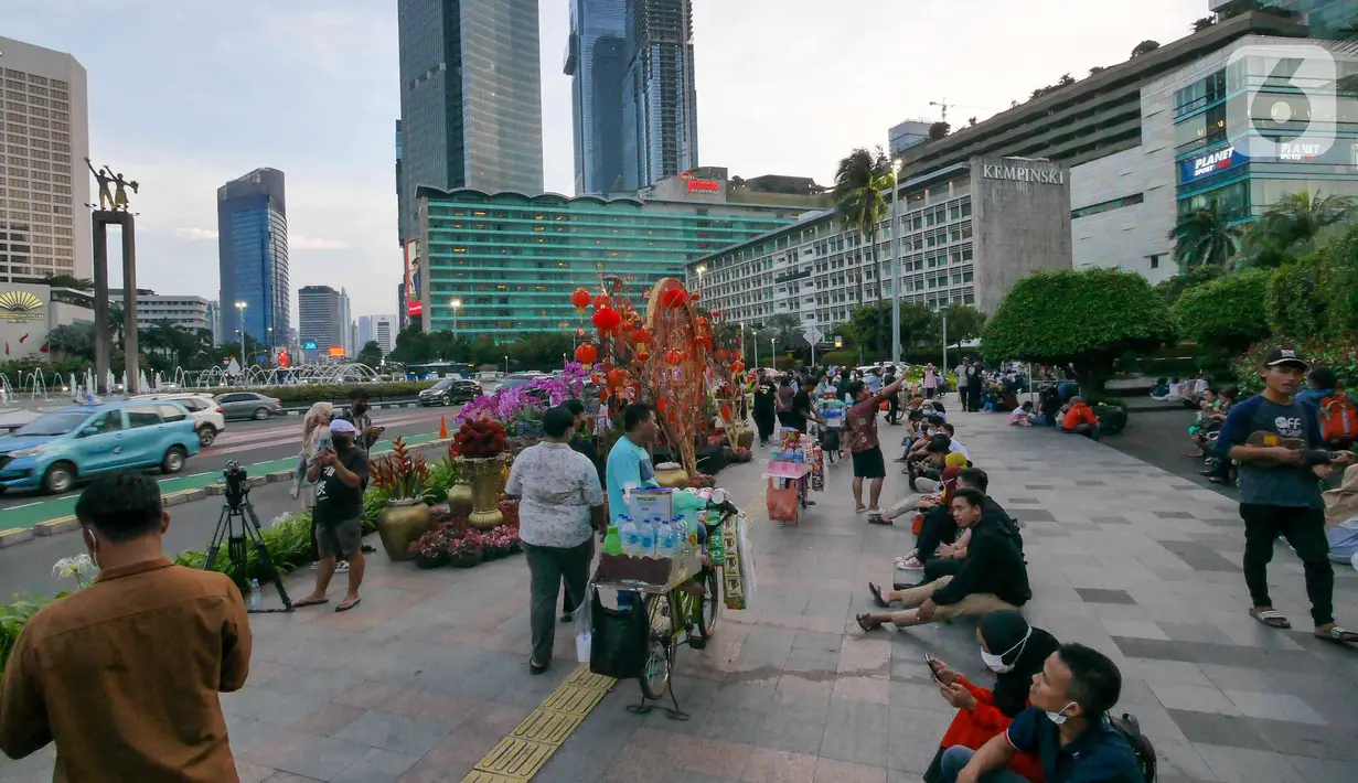 Orang-orang bersantai dekat ornamen dengan nuansa Imlek di kawasan Bundaran HI, Jakarta, Sabtu (29/1/2022). Ornamen yang didominasi warna merah dan emas ini dipasang dalam rangka menyambut perayaan Tahun Baru Imlek 2573, yang jatuh pada 1 Februari mendatang. (Liputan6.com/Herman Zakharia)