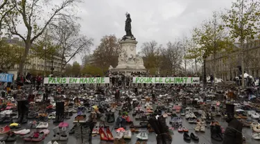 Ribuan pasang sepatu yang dikirimkan aktivis dipajang di place de la Republique, Prancis, sebagai tanda solidaritas karena pawai lingkungan di Paris dibatalkan jelang Konferensi Tingkat Tinggi Perubahan Iklim, Minggu (29/11).  (AFP PHOTO/Miguel Medina)