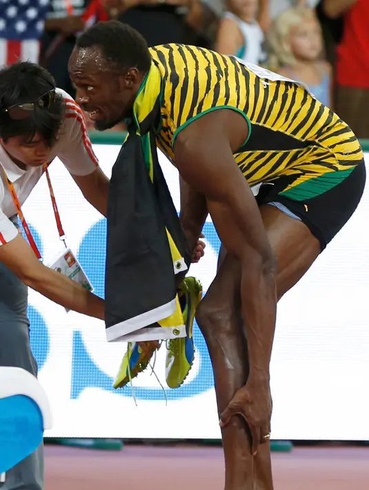 Pelari Jamaika, Usain Bolt memegangi kakinya usai tertabrak kameramen yang mengendarai skuter saat dirinya melakukan selebrasi kemenangan meraih medali emas di nomor 200 meter pada Kejuaran Dunia Atletik di Beijing, Kamis (27/8). (REUTERS/Phil Noble)