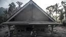 Seorang pria duduk di depan sebuah rumah yang terendam lumpur setelah letusan gunung berapi oleh Gunung Semeru di desa Kajar Kuning di Lumajang (5/12/2022). Gunung Semeru meletus pada tanggal 4 Desember memuntahkan awan abu panas setinggi satu mil dan sungai lava di sisinya sambil memicu evakuasi hampir 2.000 orang tepat satu tahun setelah letusan besar terakhirnya menewaskan puluhan orang. (AFP/Juni Kriswanto)