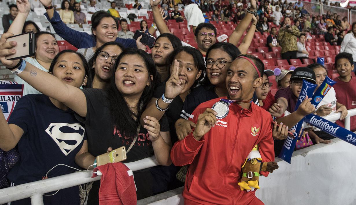 Atlet lompat jauh Indonesia, Settiyo Budi Hartanto, merayakan medali perak yang diraihnya dari cabang atletik nomor lompat jauh  T 45/46/47 Asian Para Games di SUGBK, Jakarta, Senin (8/10/2018). (Bola.com/Vitalis Yogi Trisna)