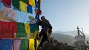 Seorang pria turun dari tiang usai memasang bendera warna-warni atau yang disebut lungta pada hari ketiga Tahun Baru Tibet di Dharmsala, India (18/2). (AP/Ashwini Bhatia)