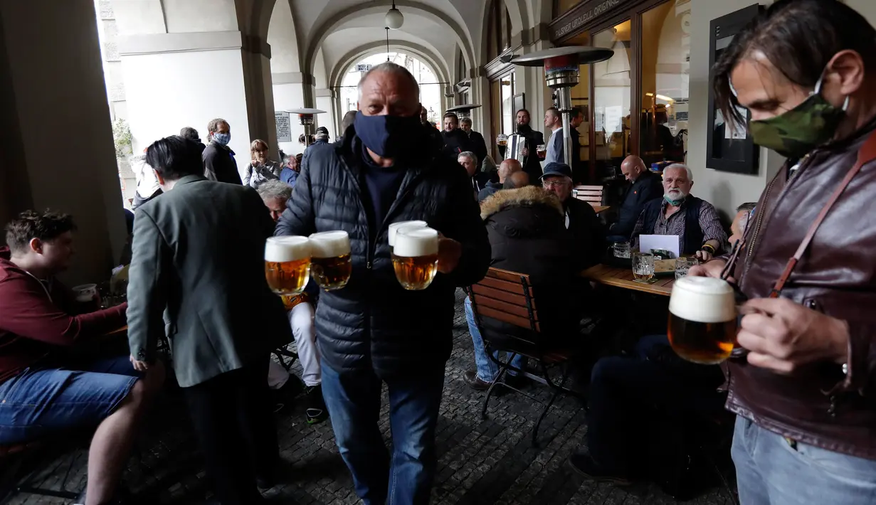 Seorang pria membawa bir di teras restoran di Praha, Republik Ceko, Senin, (11/5/2020). Dicabutnya pembatasan sosial oleh pemerintah Republik Ceko membuat sebagian besar warganya antusias merayakan kegembiraannya dengan berpesta bir. (AP/Petr David Josek)