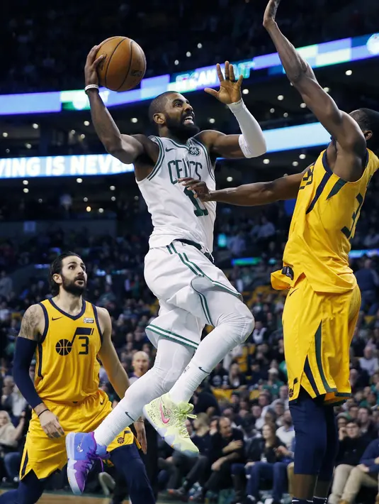 Aksi pemain Boston Celtics, Kyrie Irving (11) melakukan tembakan saat diadang pemain Utah Jazz, Ekpe Udoh pada lanjutan NBA basketball game di TD Garden, Boston, (15/12/2017). Utah Jazz menang 107-95. (AP/Michael Dwyer)